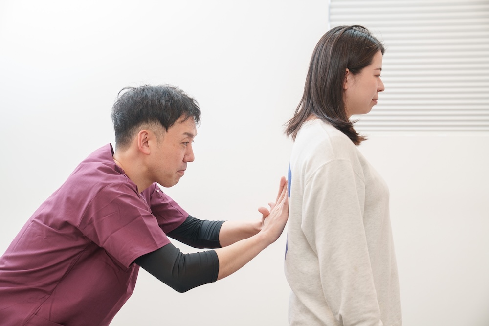 患者の背骨を検査する施術者