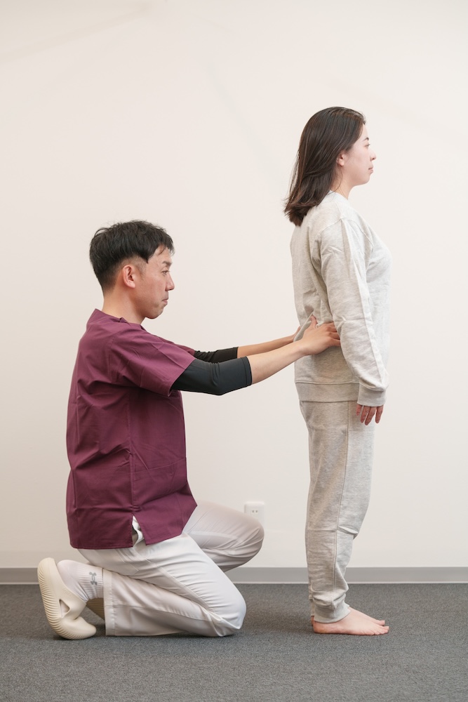 立位の患者の姿勢をチェックする施術者