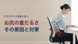デスクワークで長く座り、お尻のあたりが重だるくて手を当てる30代女性