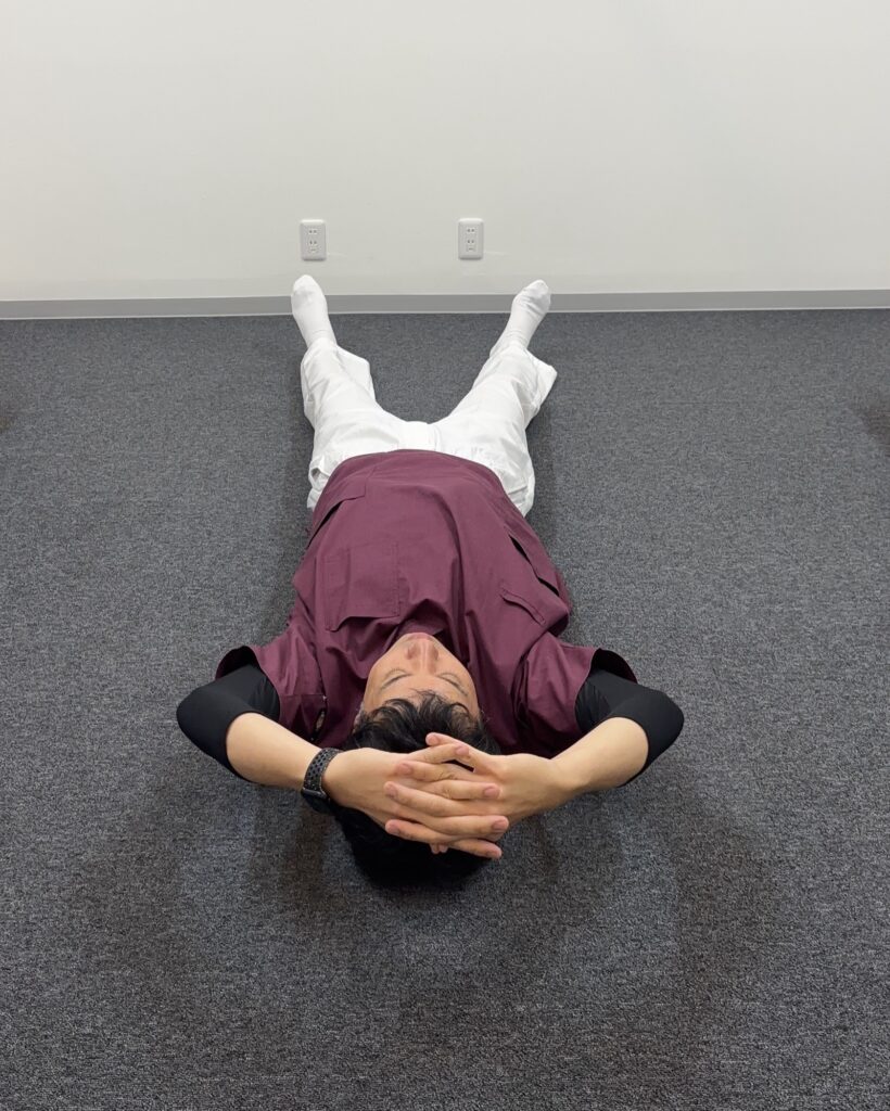 あお向けで両手の指を組み、頭の方で丸を作る