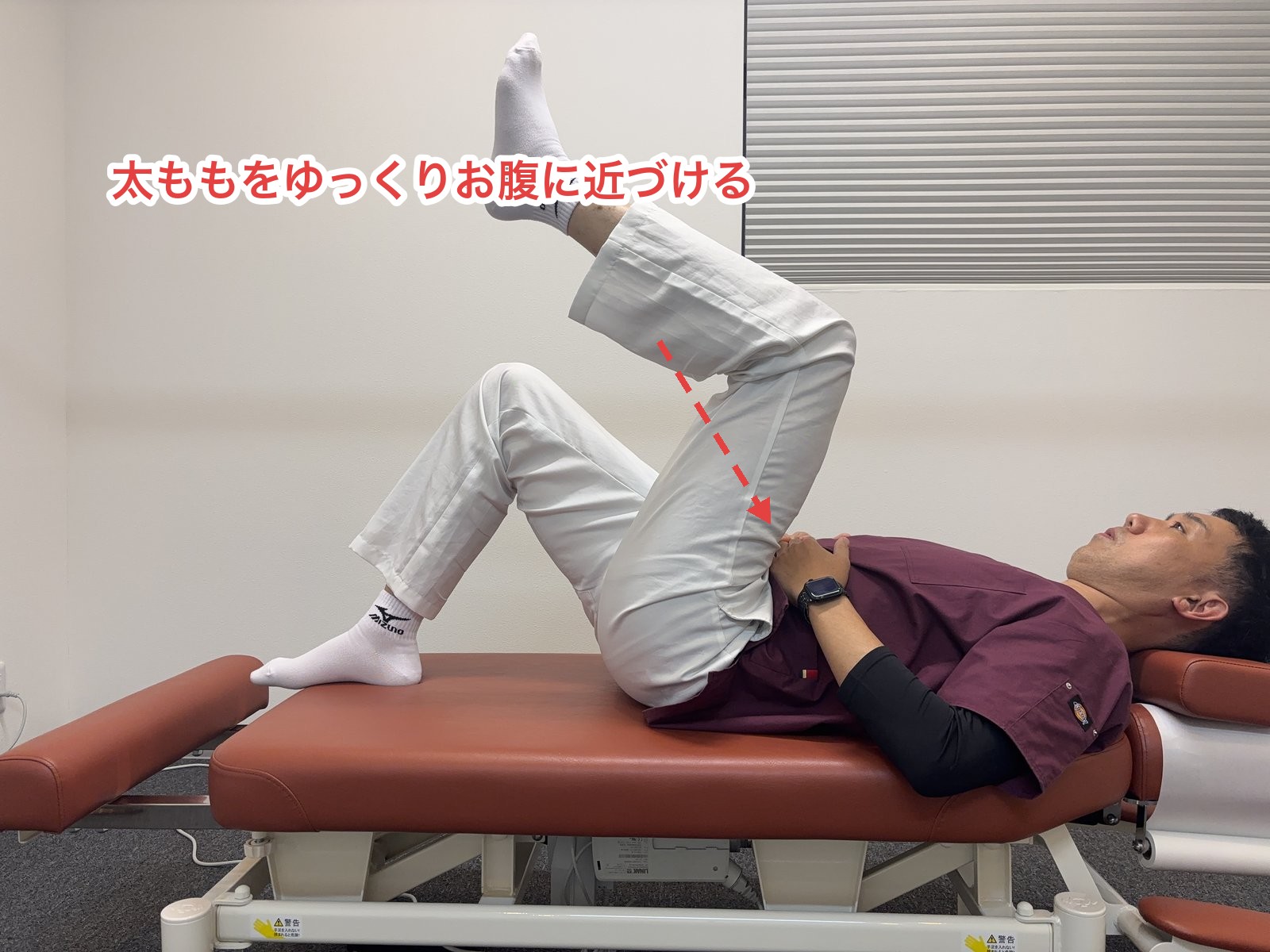 膝を90度に曲げたまま太ももをお腹に近づける様子