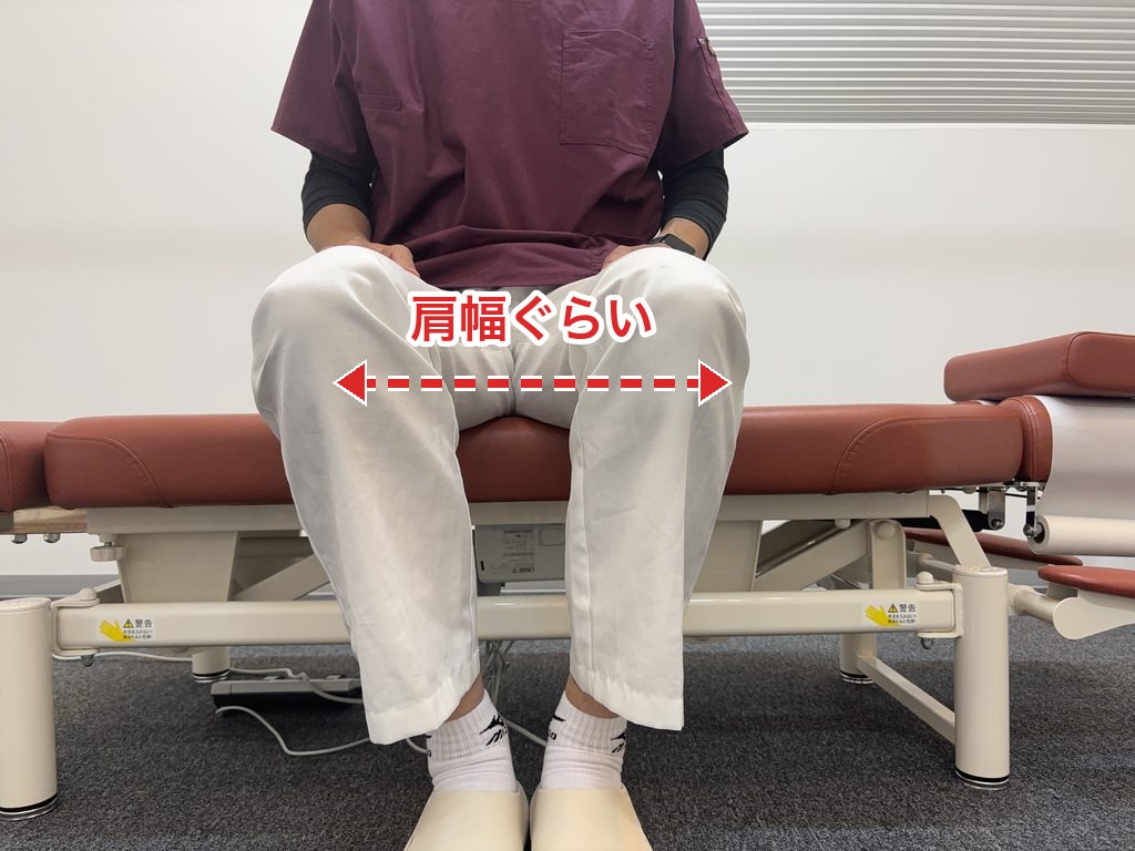 椅子に座って両膝を肩幅ぐらいに開いた様子